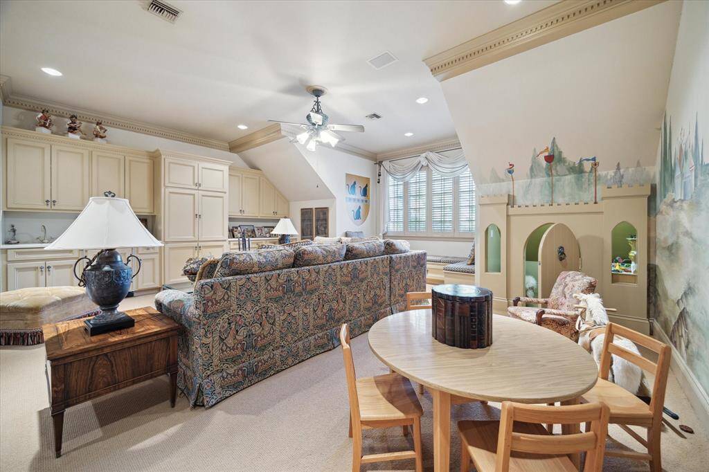 Secondary bedroom with carpeted flooring, custom millwork, plantation shutters, custom drapery, walk-in closest with built-in drawers, shelving, and hanging space, brass knobs and florescent lighting, and is en suite.