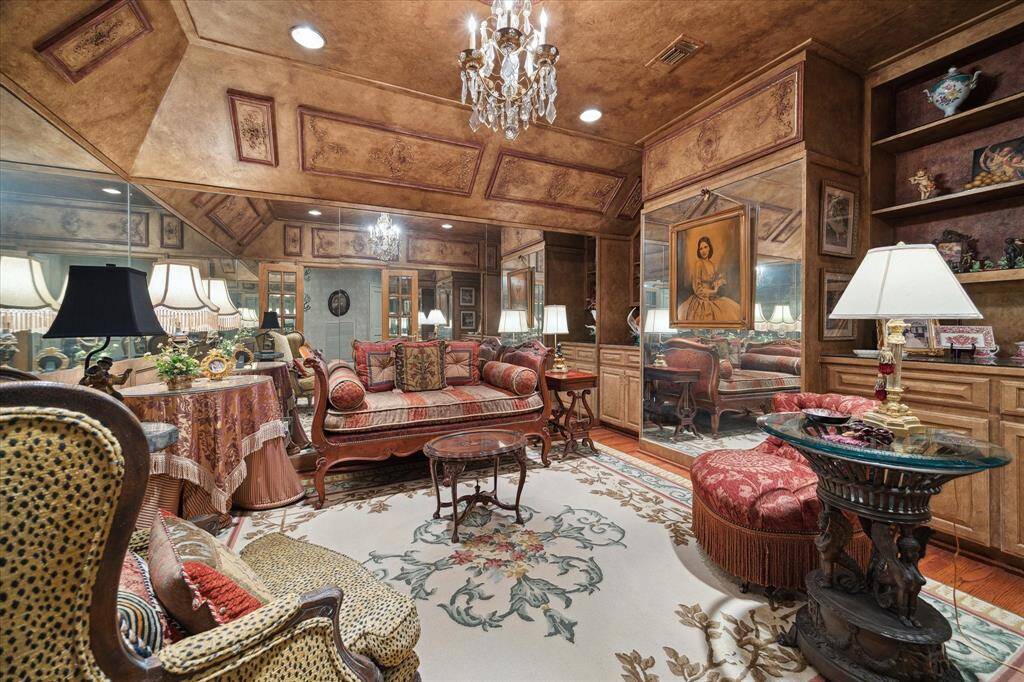 Rear staircase with Oak hardwood treads, antique crystal and bronze chandelier, carpet stair runner with brass stair rods, wood railing, and faux-finished walls.