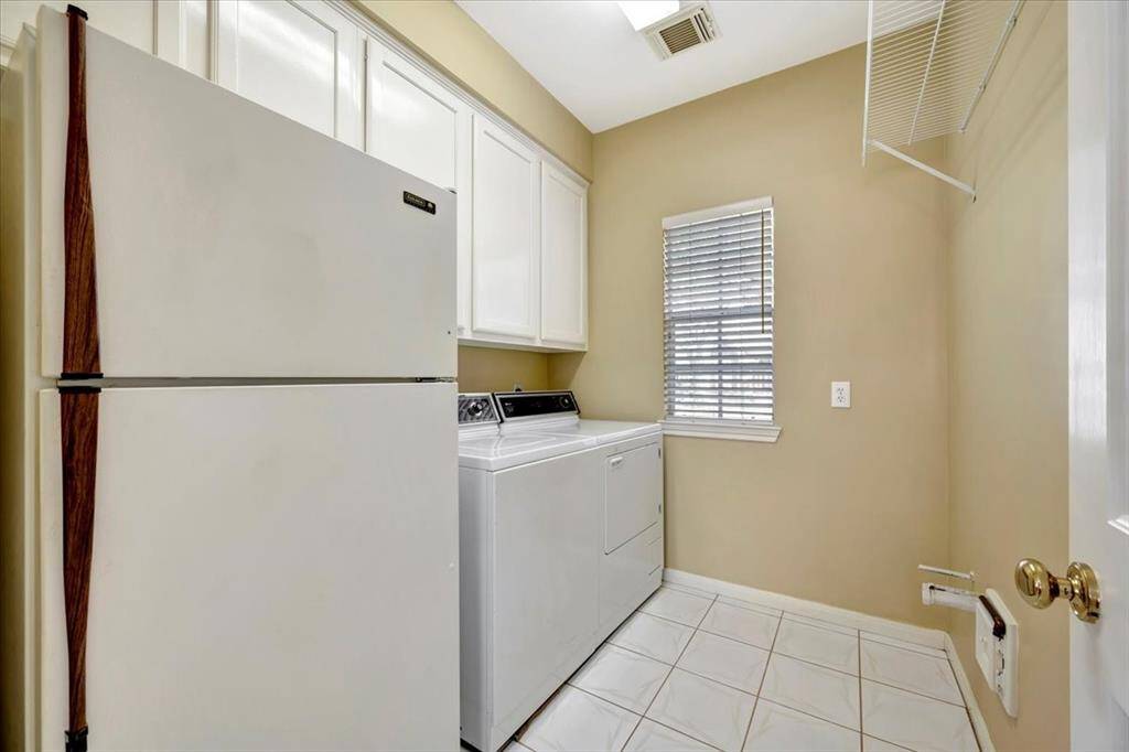 Spacious utility room with extra cabinets and room for second refrigerator.