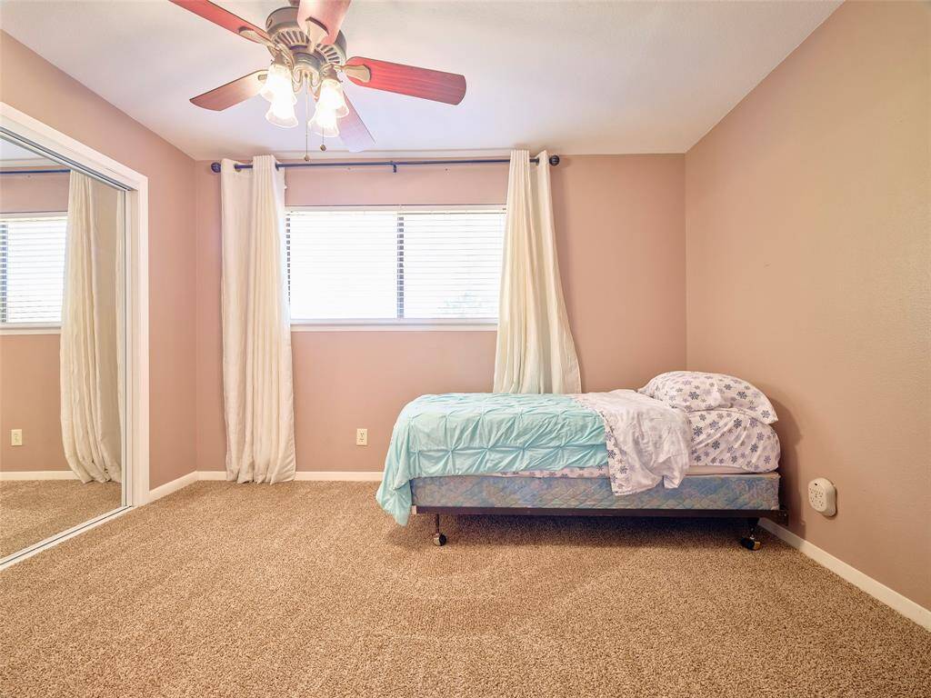 Inviting bedroom retreat featuring plush carpeting, elegant window treatments, and a lighted ceiling fan for comfort and style.