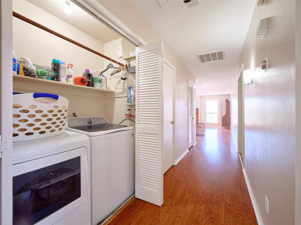 Inviting central corridor featuring gleaming hardwood floors and convenient laundry access.
