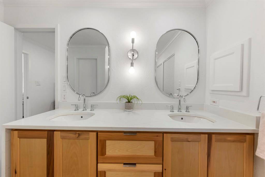 The modern vanity boasts dual sinks, sleek chrome fixtures, and stylish lighting, adding a touch of elegance to the space.