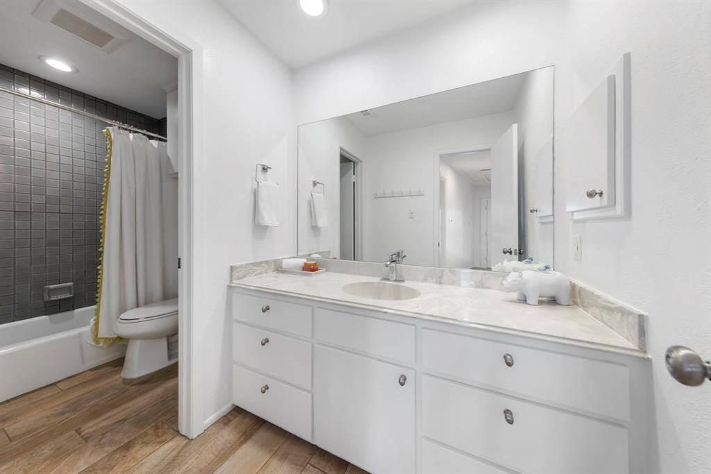 The upstairs secondary bathroom features wood-like tile flooring and a beautifully tiled shower/tub combo.