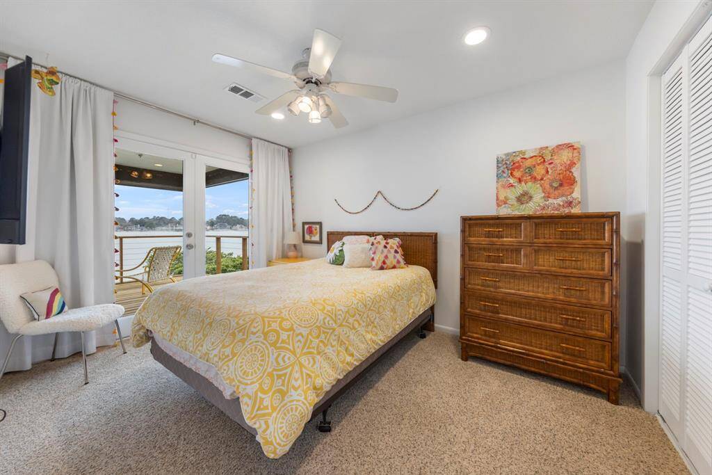 Upstairs to the right, you'll find one of three spacious secondary bedrooms, featuring plush carpet and direct access to the second-floor deck, perfect for enjoying the lake views.