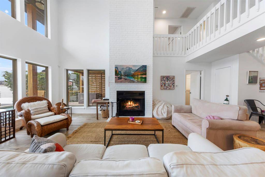 A showstopping floor-to-ceiling white painted brick wood-burning fireplace serves as the stunning focal point of the family room, adding warmth and charm.