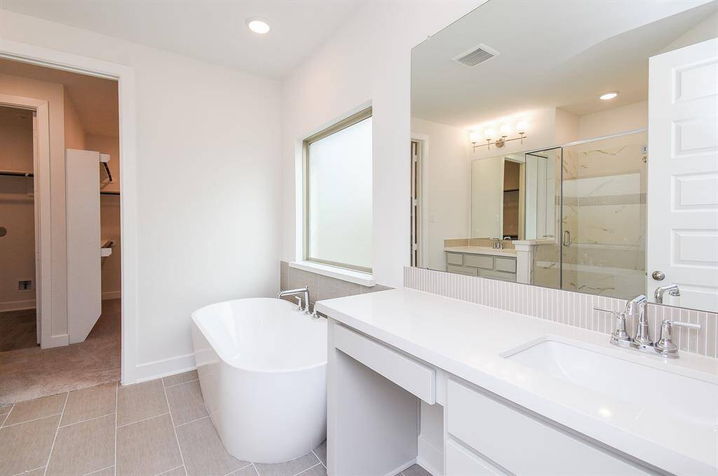Luxurious bathroom featuring dual vanities and a large soaking tub.