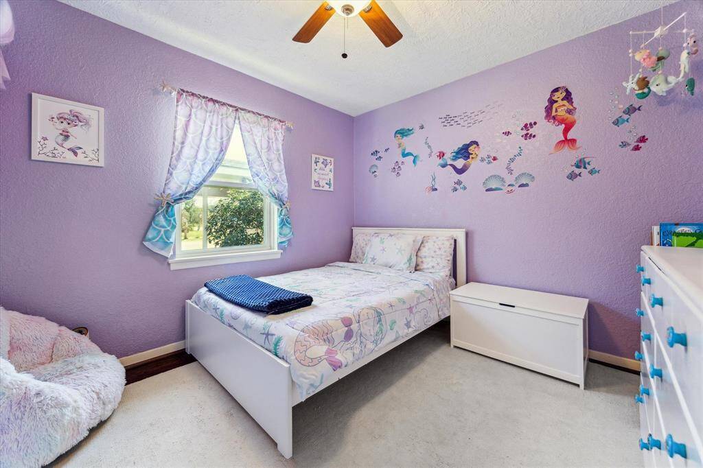 The secondary bedroom, currently transformed into a delightful little girl's haven. The room features the same engineered wood floors, and a ceiling fan for comfort. Room is easily adaptable to your needs.