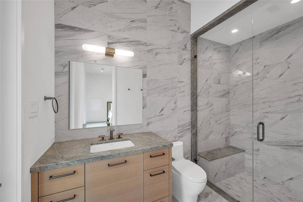 Upstairs utility room with Quartzite counters, polished chrome hardware & fixtures, a large hanging rod, under cabinet lighting, ceramic tile walls and plenty of storage cabinets.