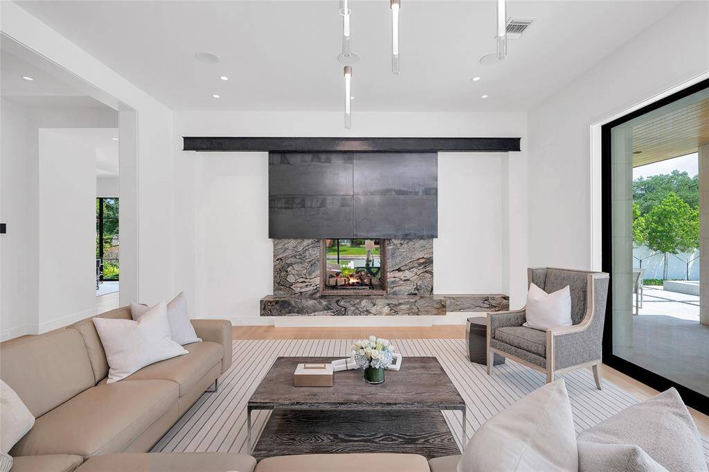 The spacious formal dining room has floor to ceiling steel windows overlooking the front yard, striped grain- patterned custom paneling, 12-foot ceilings, and a dramatic chandelier from Circa lighting.