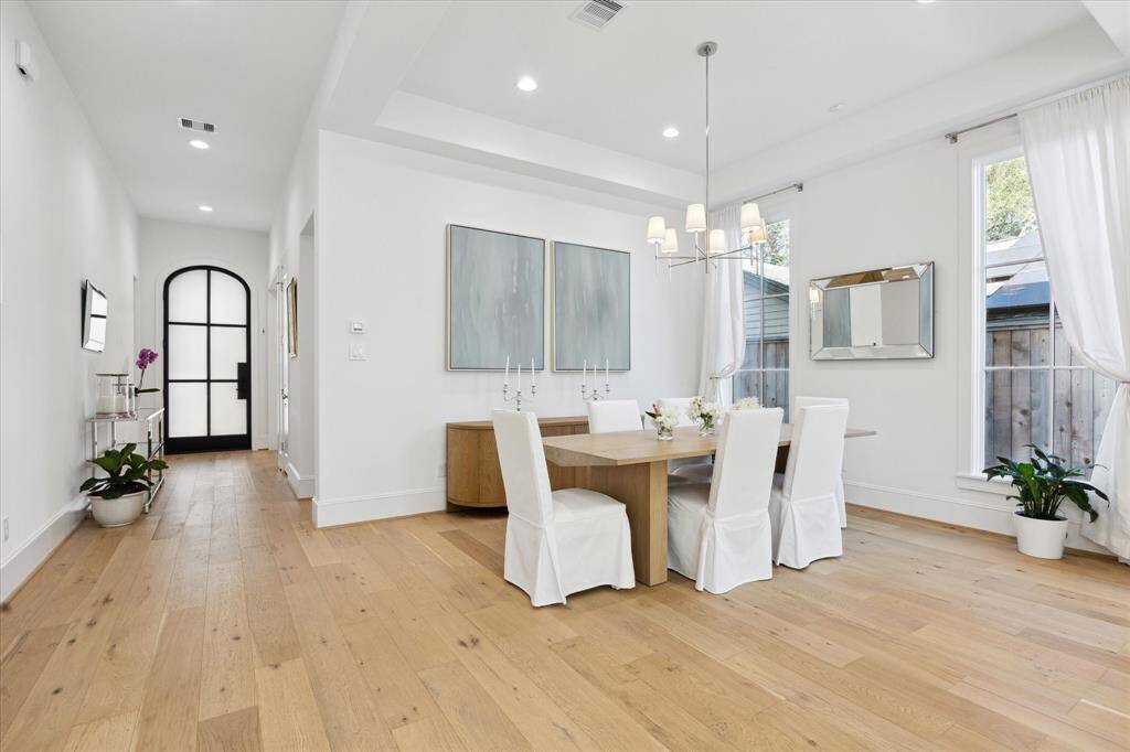 The dining room, which opens to the family room has simple but thoughtful ceiling treatments that separate the spaces. It also features a gorgeous chandelier and white draperies.
