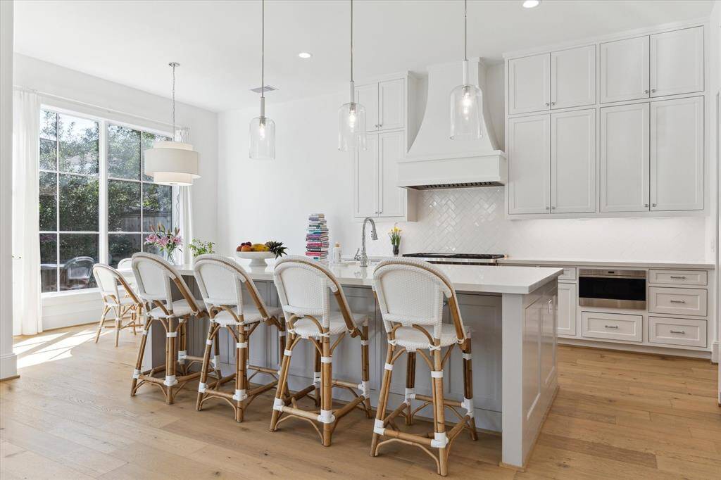 The fantastically functional and bright island kitchen features unique tile patterns, quartz counters, to the ceiling cabinets and a stunning custom venthood.