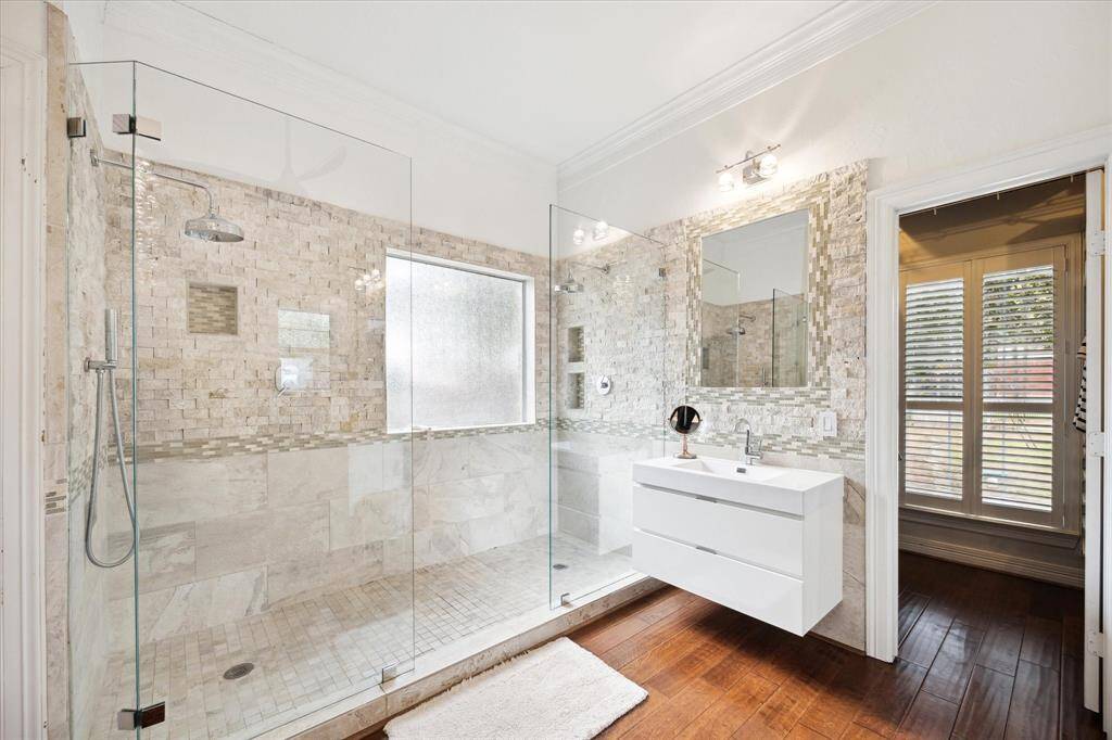 The ensuite bathroom boasts a spacious, walk-in shower designed for luxury and convenience. Featuring two shower heads on opposite walls offering a spa-like exoerinece