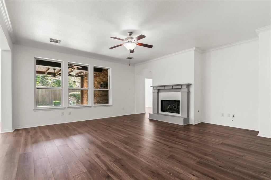 Spacious ground-level family room featuring elegant vinyl flooring, a cozy fireplace, and large windows overlooking the backyard.