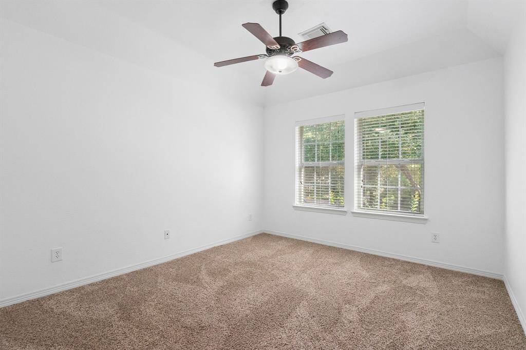 Upper-Level Retreat: Cozy and bright fourth bedroom with plush carpeting and ceiling fan, offering a tranquil view.