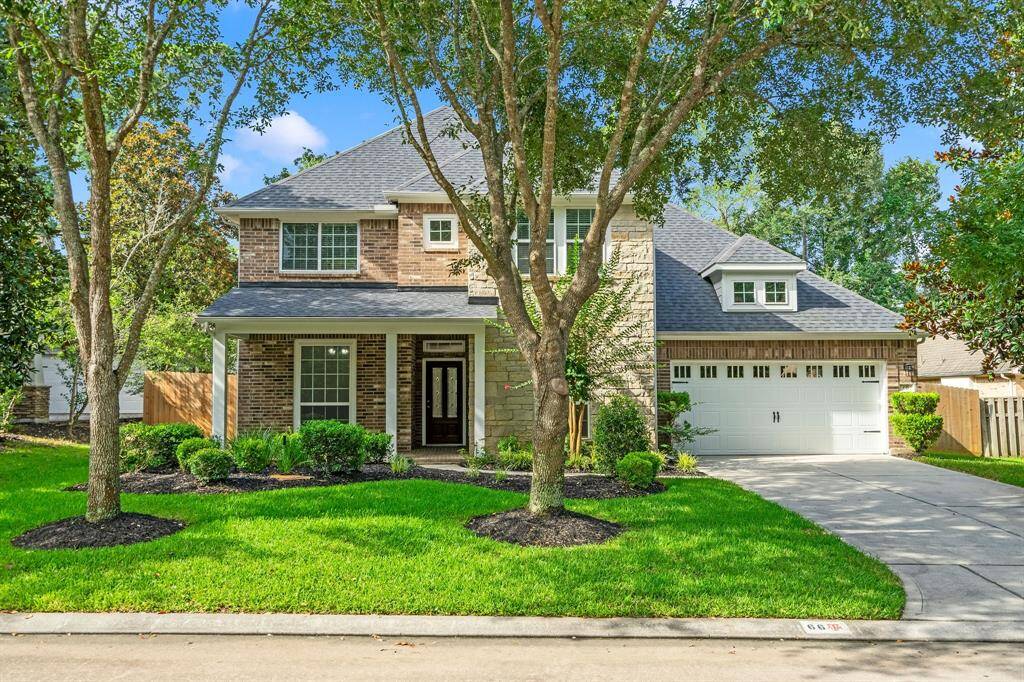 This inviting two-story home features a charming brick exterior, a spacious front yard with mature trees, and a wide driveway leading to a two-car garage. The well-maintained landscaping adds to its curb appeal, creating a welcoming atmosphere.