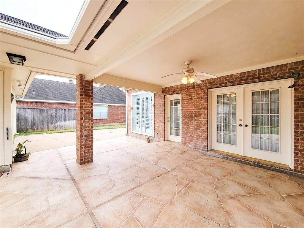 Patio from back of house looking towards driveway. Recent stamped concrete, huge garage to the left.
