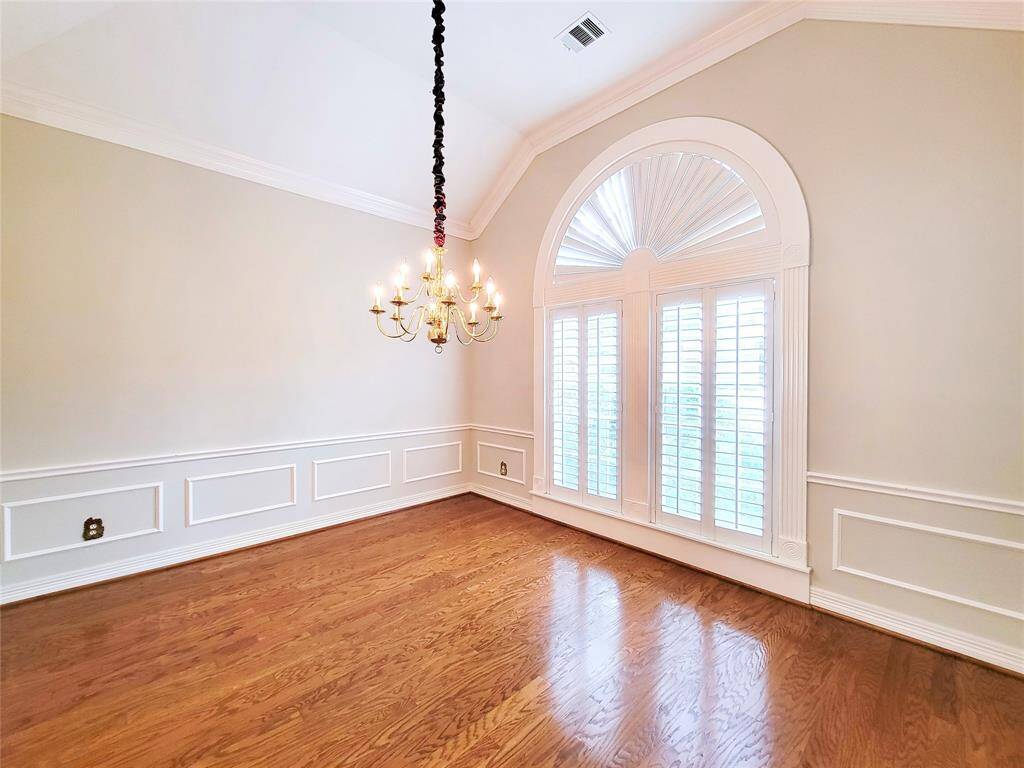 bright Dining Room right off the front entry, gleaming wood floors, large arched window with plantation shutters, crown molding & block paneling
