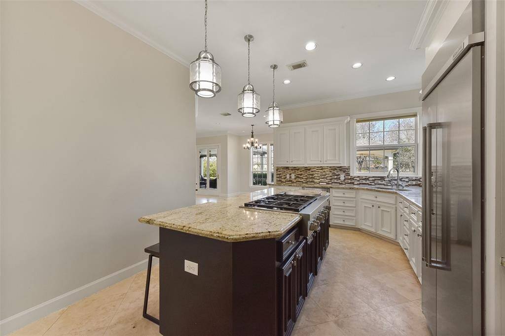 EXPANSIVE KITCHEN ISLAND FEATURING A HIGH-END GAS COOKTOP AND ELEGANT PENDANT LIGHTING.
