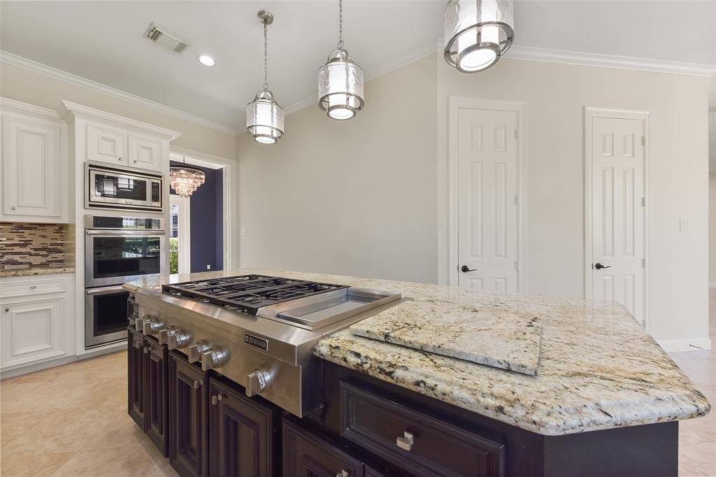 LUXURIOUS GRANITE COUNTERS COMPLEMENTED BY A STYLISH TILE BACKSPLASH AND CUSTOM CABINETRY, CREATING A CHEF’S DREAM KITCHEN.