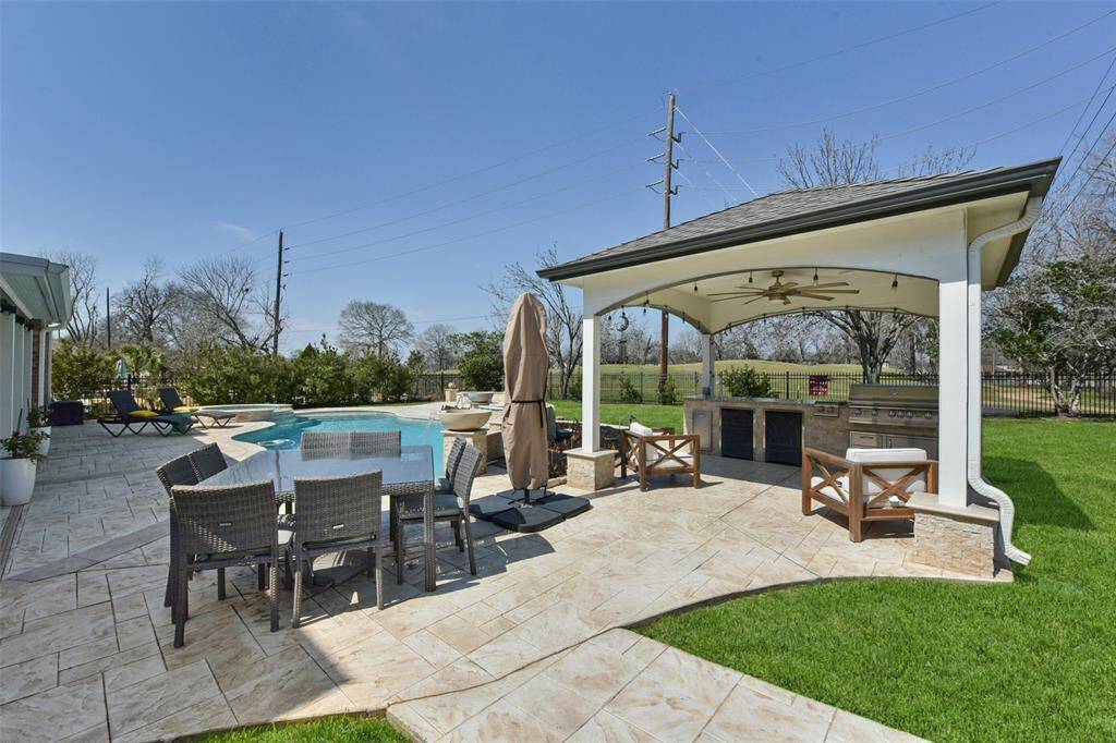 A FULLY EQUIPPED OUTDOOR KITCHEN UNDER A STYLISH GAZEBO, IDEAL FOR COOKOUTS AND ENTERTAINING.