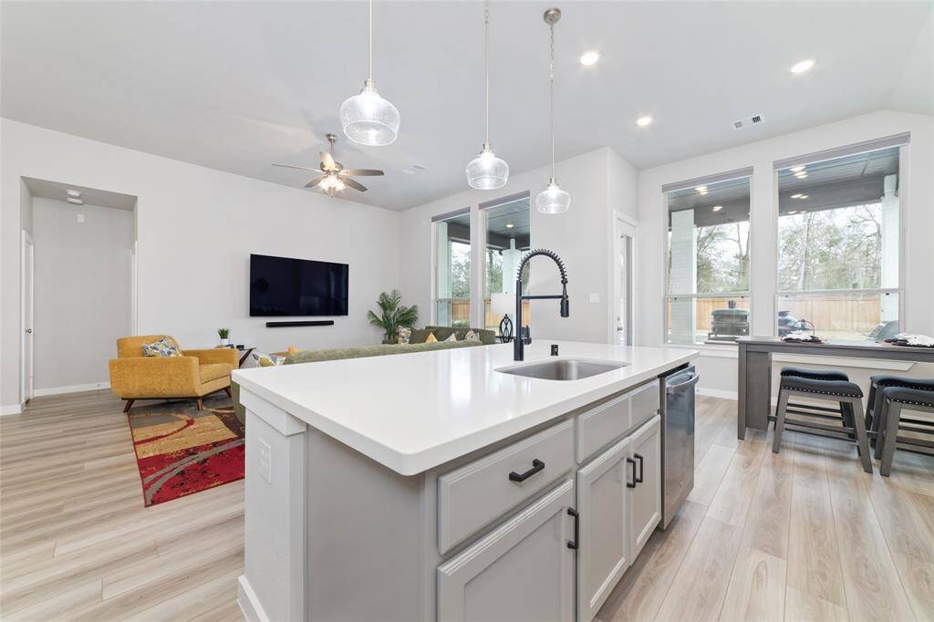 This kitchen has quartz countertops, beautiful cabinetry, large island, and large windows bringing the outdoors in.