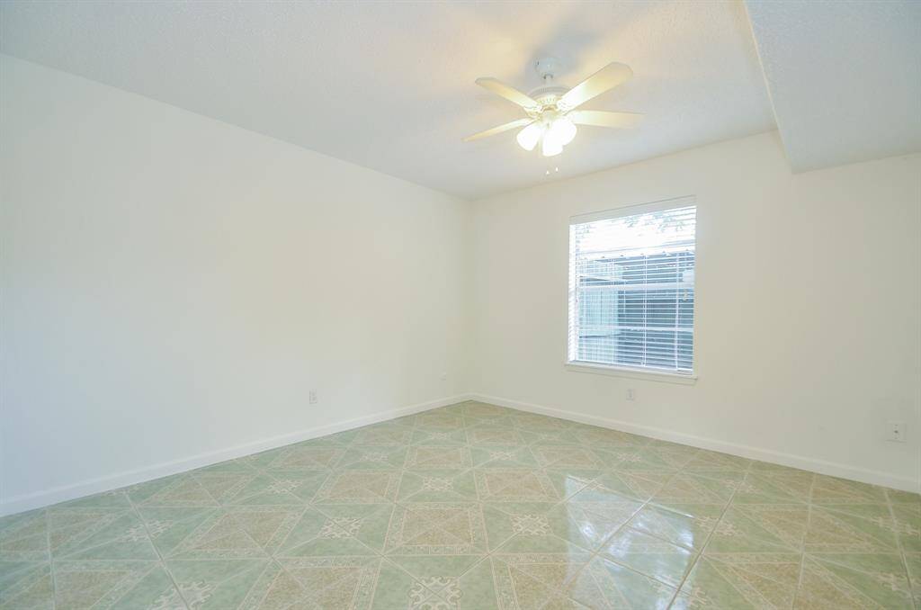 Bright room with tile flooring, neutral walls, a ceiling fan, and a window offering natural light.