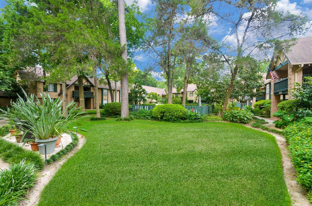 This photo showcases a charming residential area with well-maintained townhouses surrounded by lush greenery. The scene features manicured lawns, mature trees, and landscaped pathways, creating an inviting and serene community atmosphere.