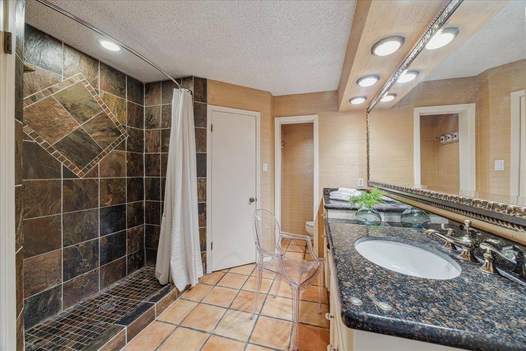 Primary bath with dual sinks, knee space for dressing vanity in the middle.  Large walk-in shower (could be converted to tub/shower combo), flanked by two walk-in closets.  Another wall of built-in draws and cabinets on the lefthand side not pictured.