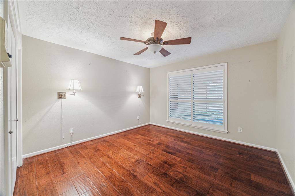 Secondary bedroom with wood floors and plantation shutters.