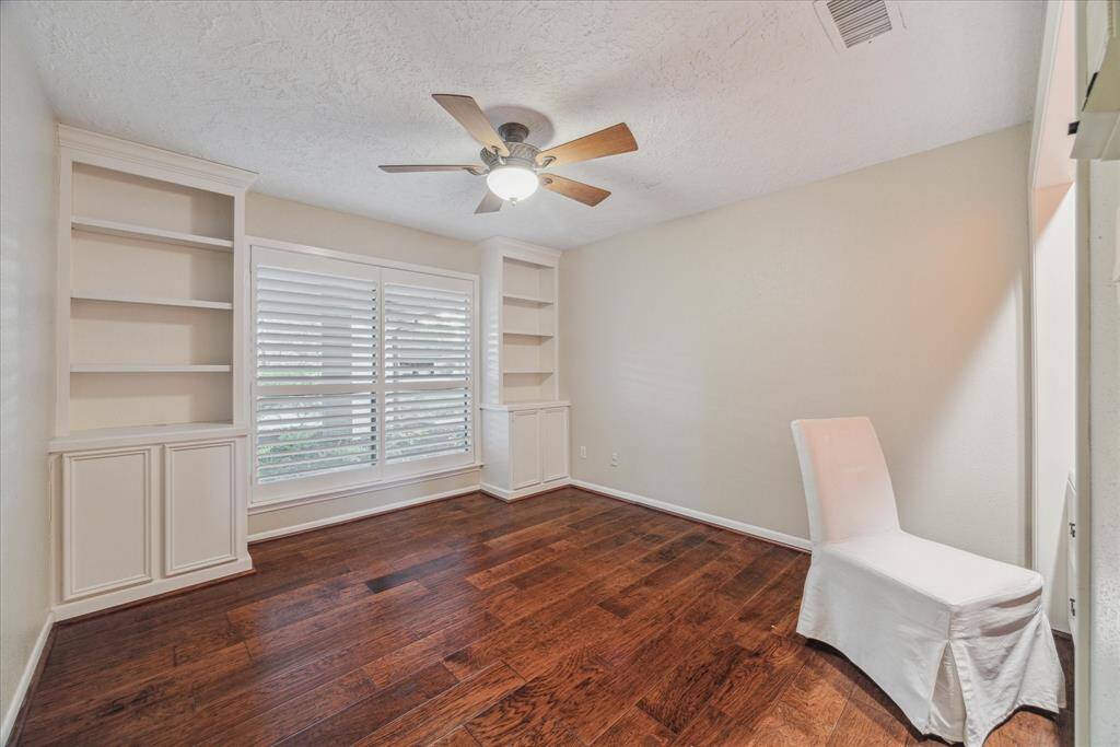 This secondary bedroom has built-ins, wood floors and plantation shutters.