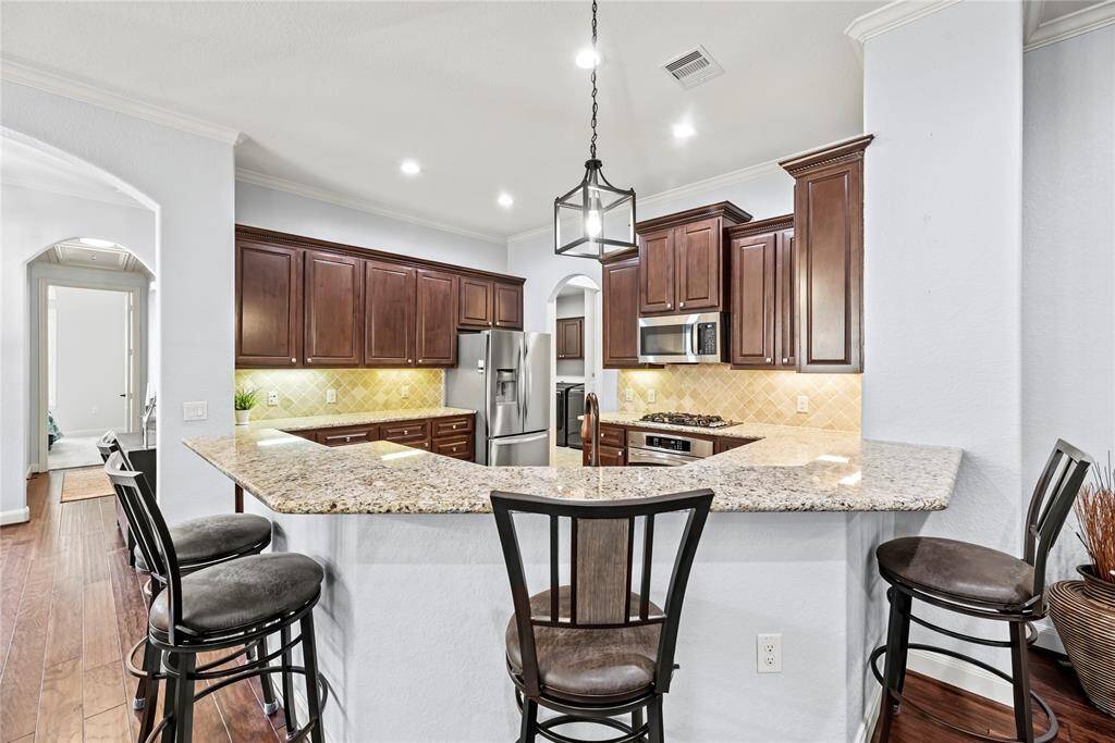 An extended bar seamlessly separates the kitchen from the family room, offering the perfect space for serving drinks and snacks to guests. Add bar stools to create casual seating, making it an inviting spot for conversation and everyday gatherings.