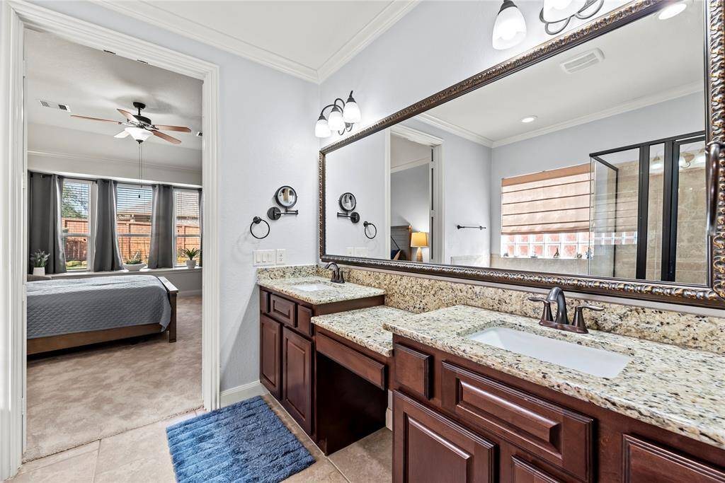 The ensuite bathroom offers an extended dual sink vanity with a granite countertop, custom mirror, and coordinating vanity lights above. Thoughtfully designed, you'll also find a medicine cabinet, ample storage in the vanity and linen closet, and a convenient knee space so you to sit while you primp