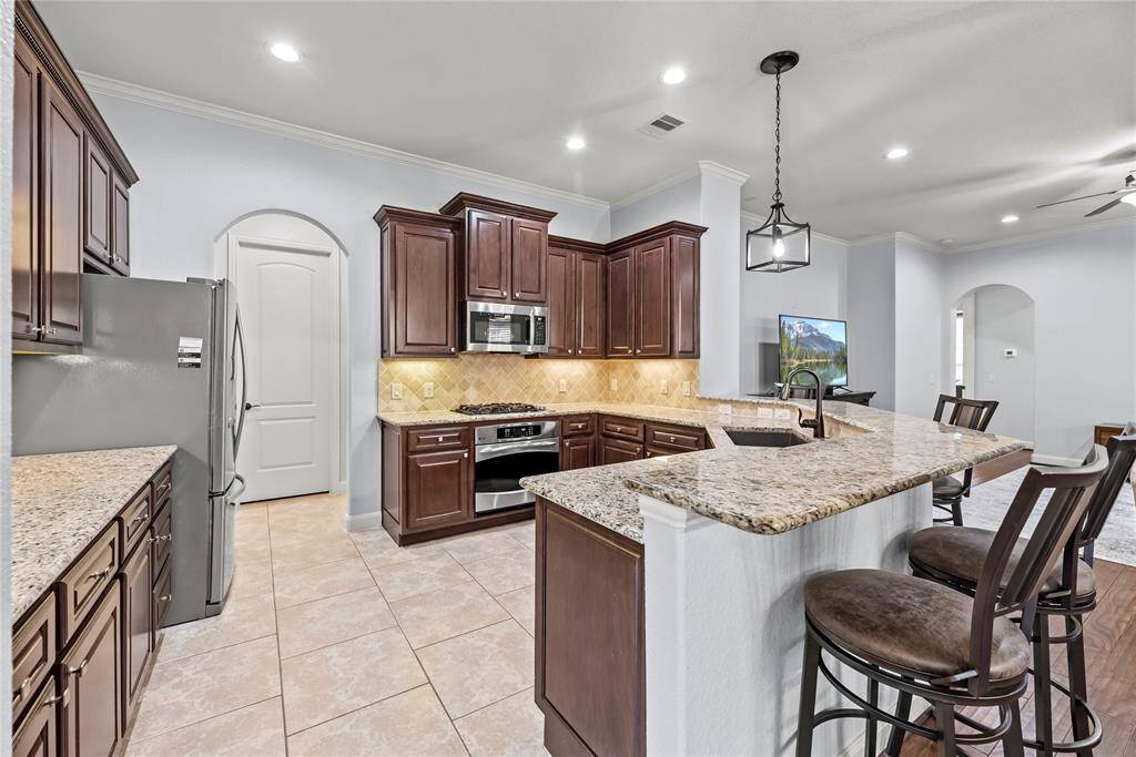Show off your culinary skills in this beautifully appointed kitchen. Find rich wood cabinetry with some convenient pull-outs, granite countertops, designer tile backsplash with under-cabinet lights, sleek stainless-steel appliances (including a recent microwave), an upgraded farmhouse sink with elegant overhead lighting.
