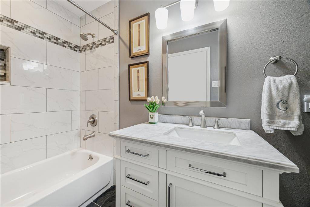 This hall bath has a tub and shower combination with marble-look subway tile.  A marble countertop adorns the vanity and offers nice storage options in the cabinet and drawers.