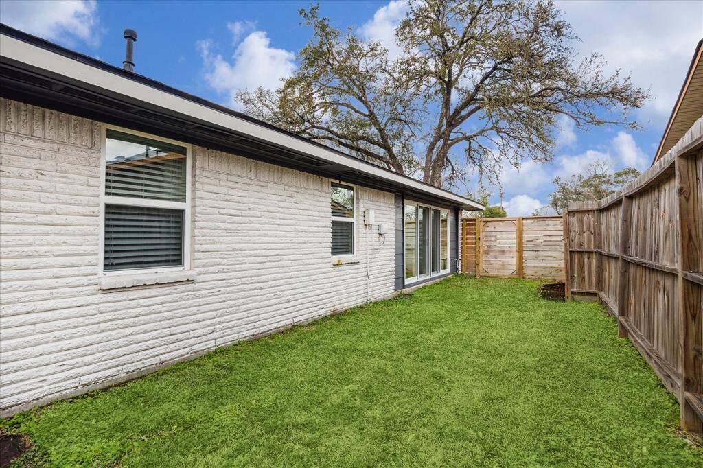 The side yard leading to the front yard beyond the gate.  Notice the double paned window and set of wide double doors which lead to the dining room.  This home has 4 sides of brick.
