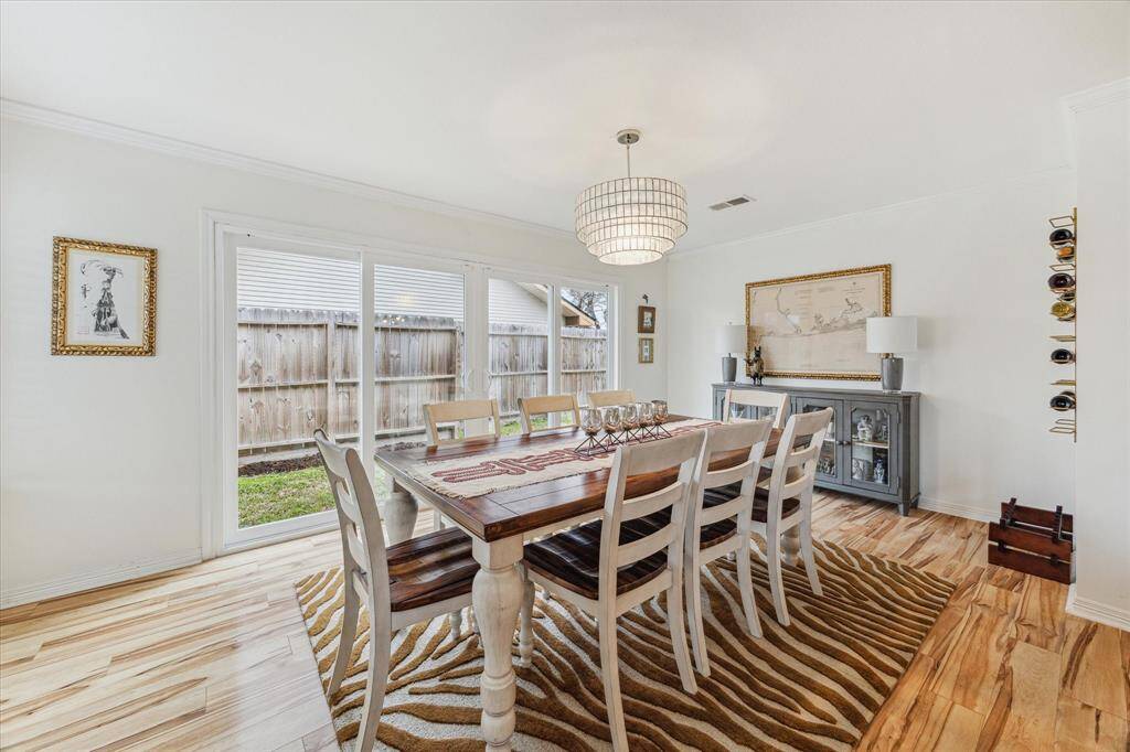 This view of the dining room shows the amazing wall of windows with two large sliding doors that open onto the side yard. The flooring is a wood look laminate that is durable and easy to care for.
