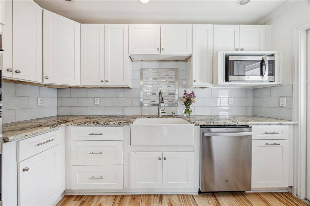 Another view of this bright kitchen shows the farm style sink, tile backsplash and brushed nickel fixtures and hardware.  A door on the right opens onto the patio and pool area.