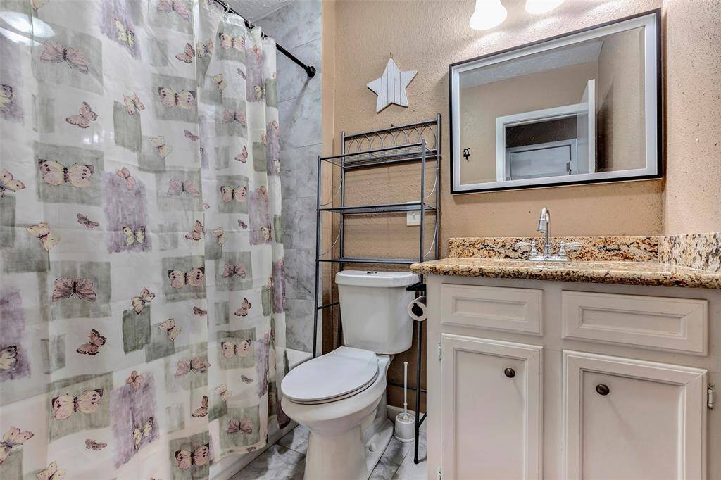 The secondary bathroom has a shower/tub combo with an updated vanity and granite countertops.