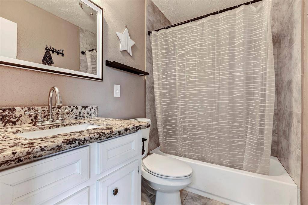 The primary bathroom features a shower/tub combo and an updated vanity with granite countertops.
