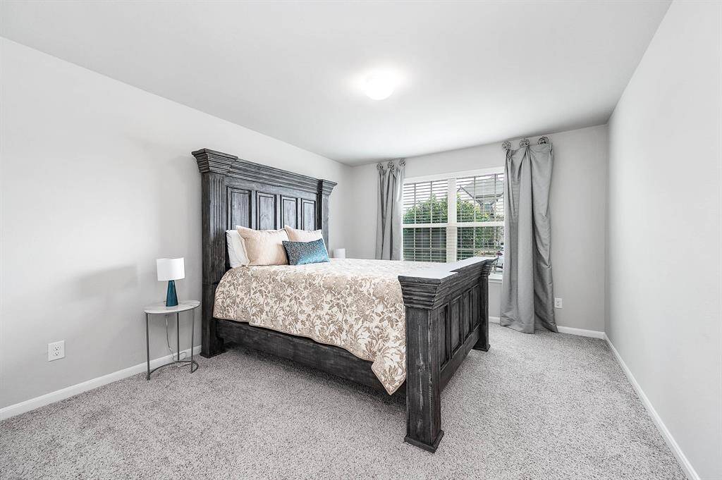 This secondary bedroom features a spacious layout with neutral walls, a walk in closet and carpeted flooring.