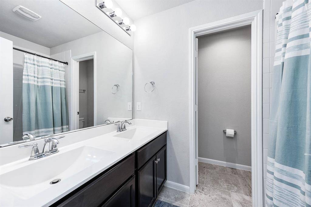 This bathroom features a modern dual-sink vanity with sleek fixtures and a large mirror. I