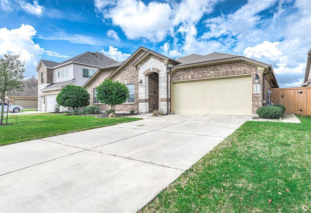 The driveway is spacious, and the exterior has a combination of brick and stone accents.
