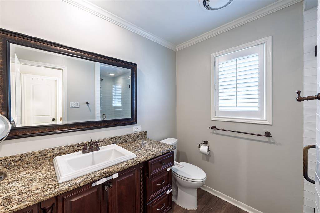 Primary ensuite offers granite countertop, framed mirror, and frameless shower.