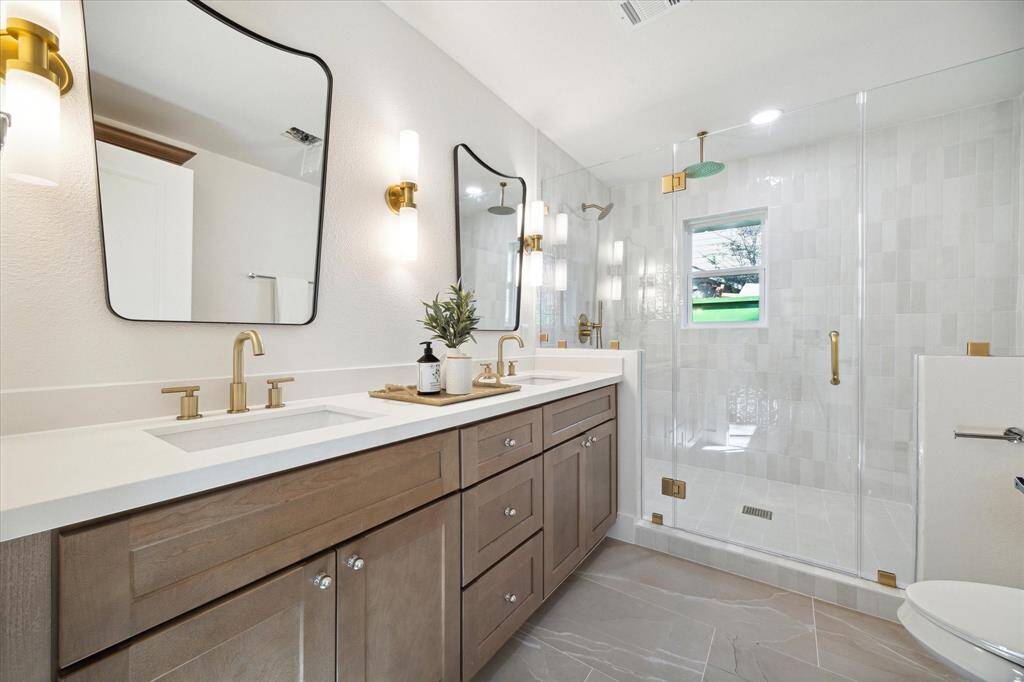 THE ENSUITE BATHROOM BOASTS AN ENLARGED WALK-IN SHOWER WITH DOUBLE HEAD SHOWER TRIM AND SEEMLESS SHOWER GLASS. THE VANITY AREA FEATURES NEW DOUBLE SINKS WITH DESIGNER KARMEL CABINETRY, FAUCETS, MIRRORS, VANITY LIGHTS AND PURE WHITE QUARTZ COUNTERTOP.