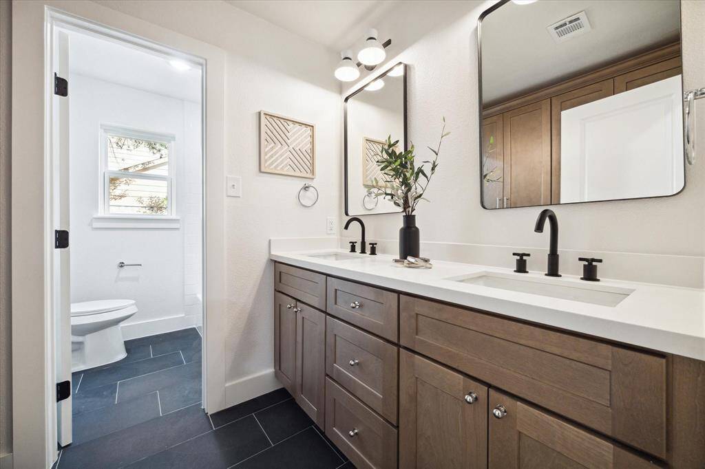 SECONDARY BATHROOM WITH KARMEL CABINETS, QUARTZ COUNTER, DOUBLE SINKS AND CUSTOM VANITY FITTINGS.