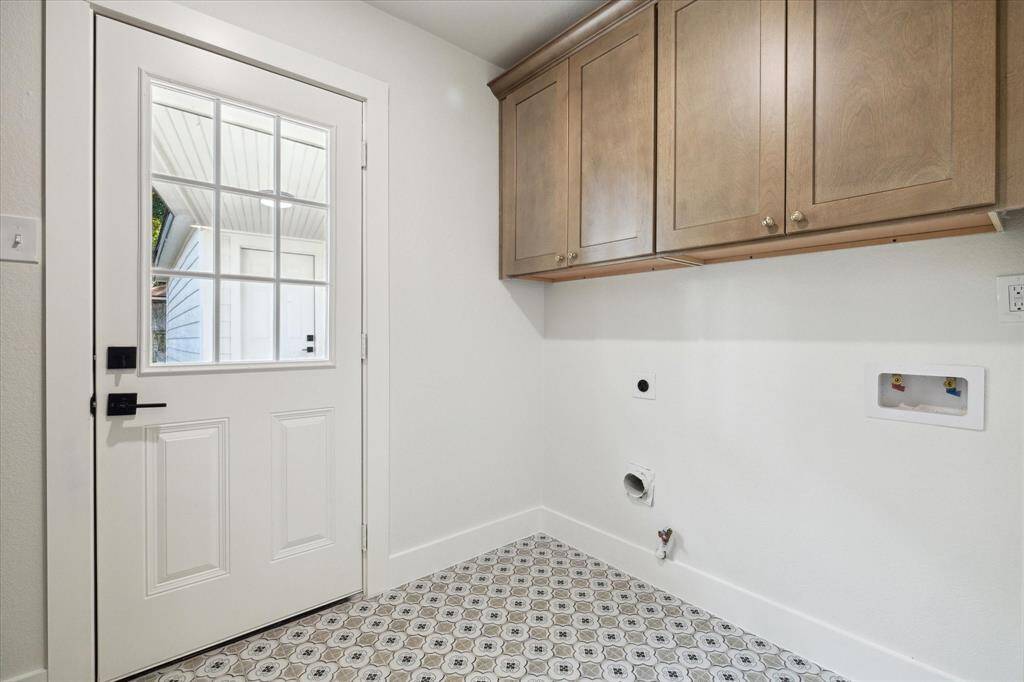 SPACIOUS LAUNDRY ROOM WITH CUSTOM CABINETS AND BACK DOOR LEADING TO THE GARAGE.