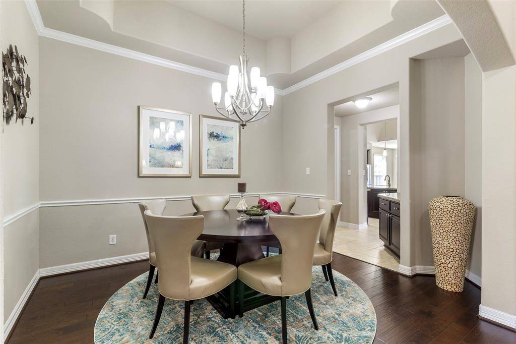 This dining room features wood floors, tray ceilings, crown molding, chair rail, and a chandelier.