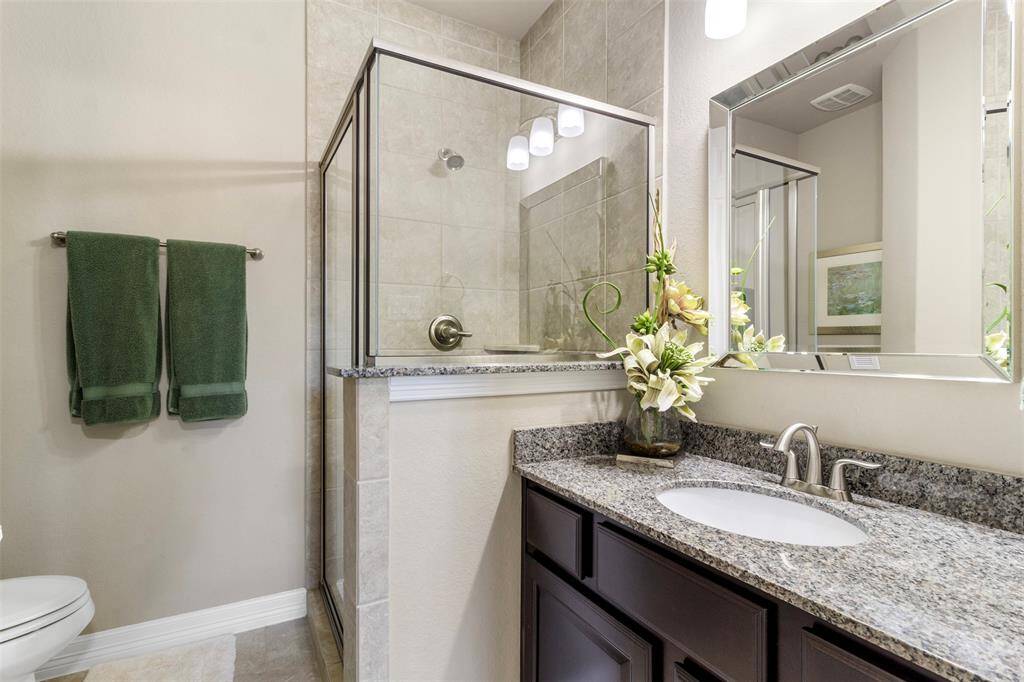 Secondary bathroom features a walk-in shower with tile surround and long vanitywith plenty of counter space.