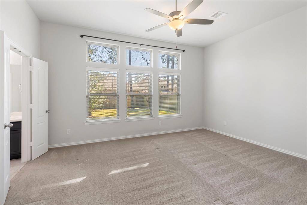 The spacious primary suite has 3 large windows with a peaceful view of the greenspace in the backyard.