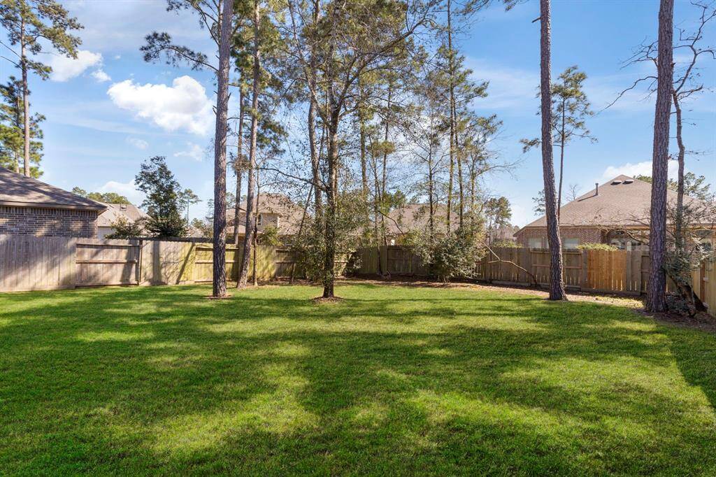 Large fenced back yard with mature trees.